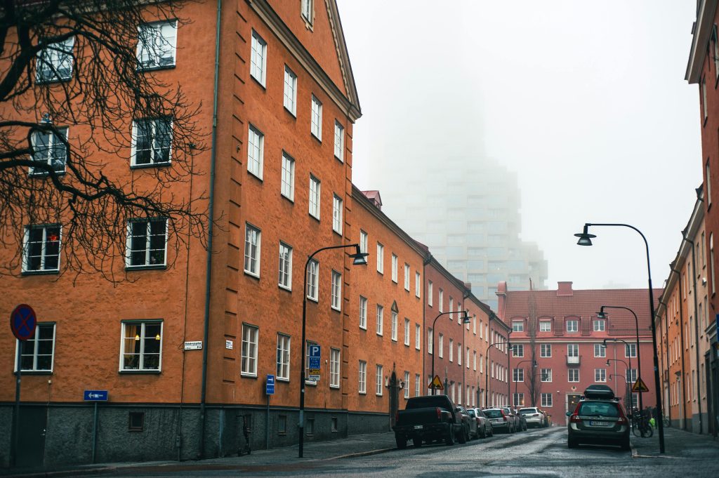 A foggy day on a residential street in Stockholm with parked cars and classic architecture.